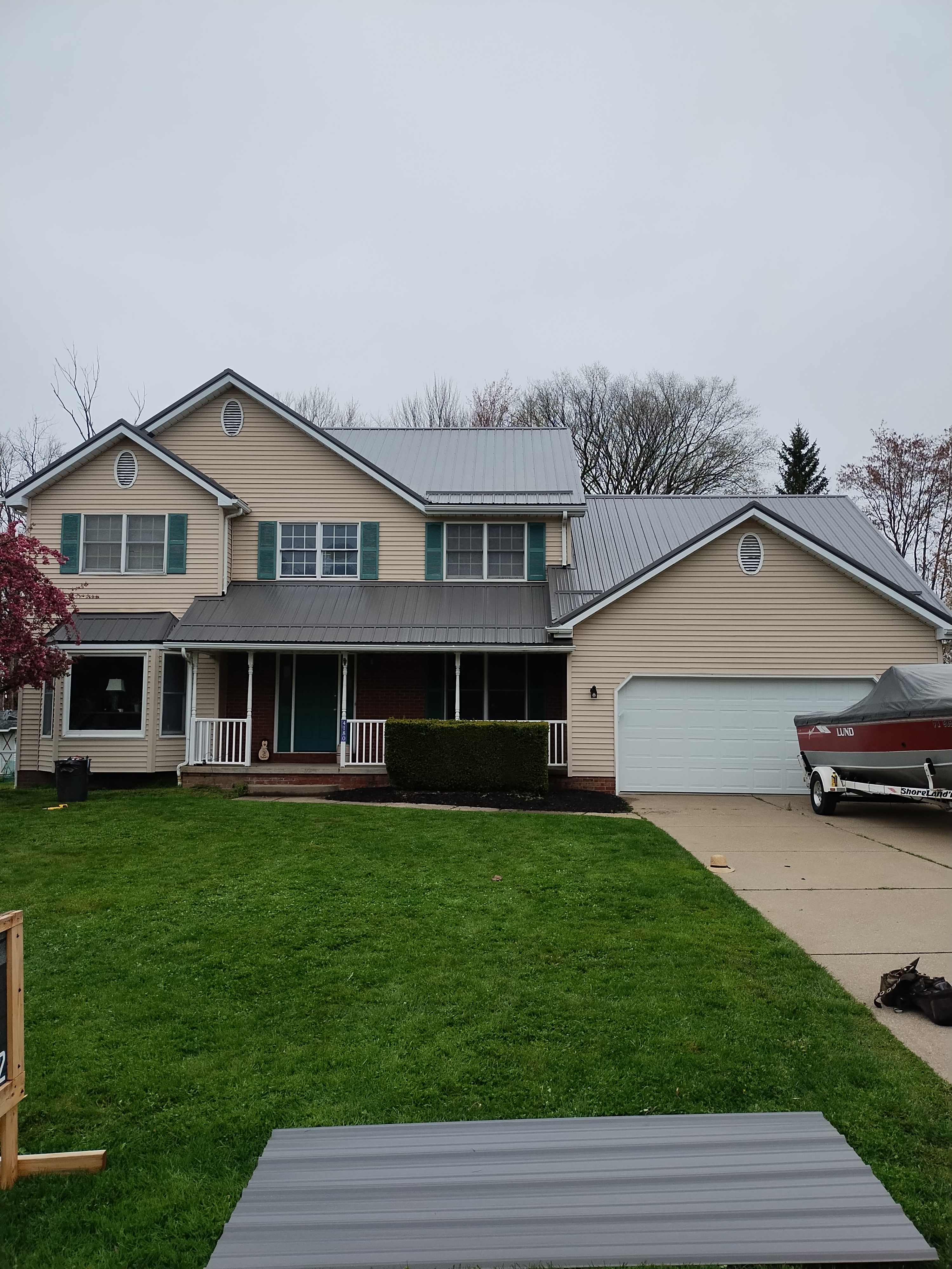 Tan two-story home with a finished standing seam metal roof by Troyer's Contracting